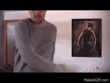 a man is standing in front of a painting of a woman on a wall .