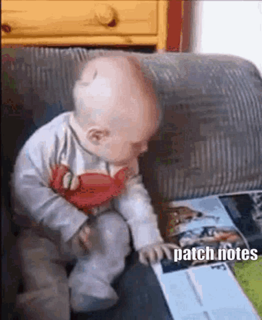 a baby is sitting on a couch reading a book and holding a toy .