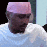 a man wearing a white shirt and a pink headband looks down