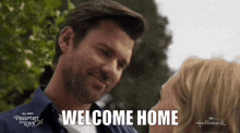 a man and woman are looking into each other 's eyes and the words welcome home are visible
