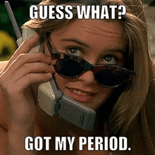 a woman wearing sunglasses is talking on a cell phone and guess what ? got my period .