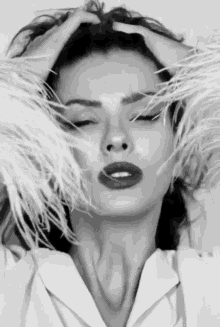 a black and white photo of a woman with feathers covering her face