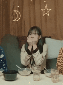 a girl sitting at a table with bowls and glasses with a star and a crescent moon in the background