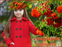 a little girl wearing a red coat and a wreath of berries