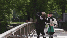 a man and a woman are standing on a bridge with the words lay co day