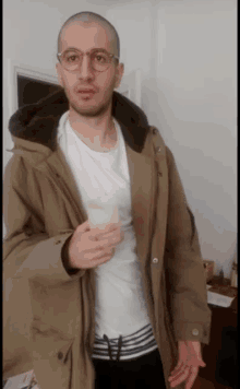 a man wearing glasses and a jacket holds a cup of coffee