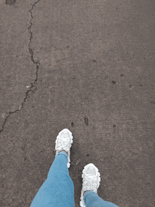 a person 's feet wearing white sneakers and blue jeans