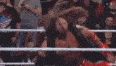a wrestler in a ring with a crowd behind him and a shirt that says ' wwe ' on it