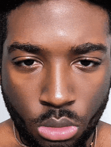 a man with a beard and pink lips looks at the camera