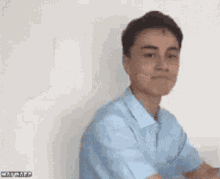 a man in a blue shirt is covering his face with his hands