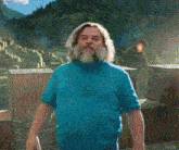 a man with long hair and a beard is wearing a blue shirt .