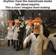 a group of people standing on a sidewalk wearing beaker masks on their heads .