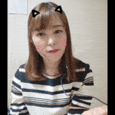 a woman wearing a striped shirt and a headset with cat ears on her head