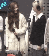 a woman wearing headphones is holding a microphone while standing next to another woman