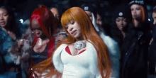 a woman with long red hair is dancing in front of a crowd of women .
