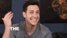 a man in a grey shirt is smiling and says the
