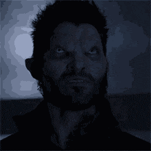 a man with a beard and fangs is screaming in the dark .