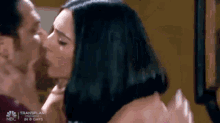 a man is kissing a woman on the cheek in a scene from a tv show .