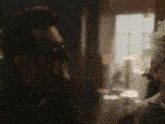 a man is talking on a cell phone in a dark room while another man looks on .