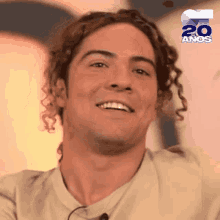 a man with curly hair is smiling and wearing a shirt that says 20 anos on it