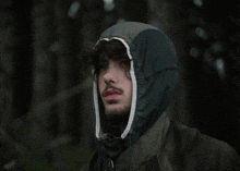 a man wearing a hooded jacket looks to his left
