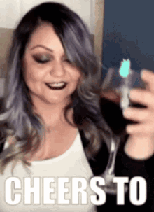 a woman with purple hair is holding a glass of wine and cheers to the camera