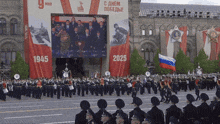 soldiers march in front of a large sign that says 1945 2025