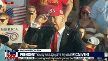 a man in a suit and tie is speaking into a microphone while wearing a usa hat
