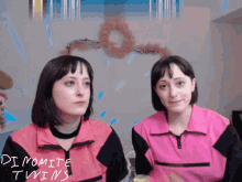two women in pink jackets with dynamite twins written on them