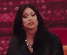 a woman with long black hair is sitting on a couch .