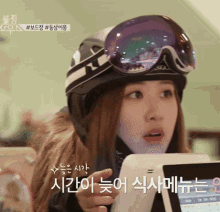a woman wearing a ski helmet and goggles is pointing at a screen