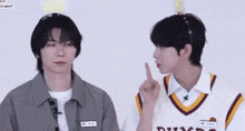 two young men are sitting next to each other and one of them is pointing at the other .