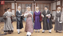 a group of young men are standing next to each other wearing traditional korean clothing .