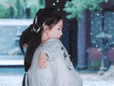 a woman in a white dress is holding a child on her shoulder