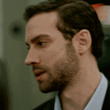 a man with a beard wearing a suit and a blue shirt