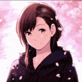 a girl in a black hoodie is standing in front of a pink background