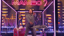 a man is dancing in front of a neon sign that says " mambo 2 "