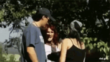 a man and two women are standing next to each other in a forest .