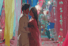 a man and a woman kissing in front of a colorful background