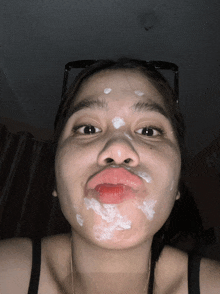 a woman with white cream on her face making a face