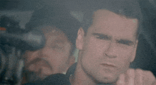 a close up of a man 's face with a man in the background wearing sunglasses .