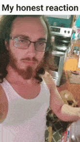a man wearing glasses and a white tank top is standing in a kitchen with a dog