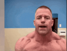 a shirtless man is standing in front of a blue wall with his mouth open