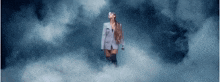 ariana grande is standing in the clouds wearing a suit and thigh high boots .