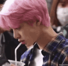 a close up of a person with pink hair drinking from a straw .