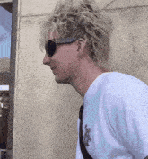a man wearing sunglasses and a white shirt with a lion on it