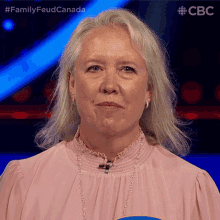 a woman in a pink shirt is standing in front of a sign that says cbc