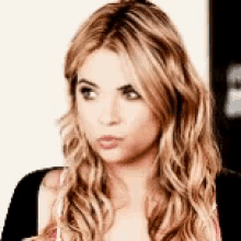 a close up of a woman 's face with blonde hair and a black shirt .