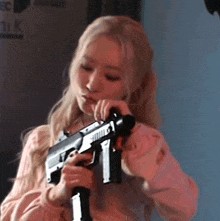 a woman in a pink shirt is holding a gun .