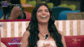 a woman is laughing in front of a screen that says grande